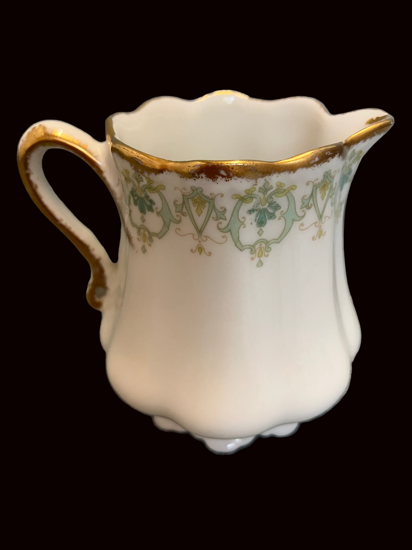 Decorative ceramic pitcher with gold and green patterns on a textured gray background
