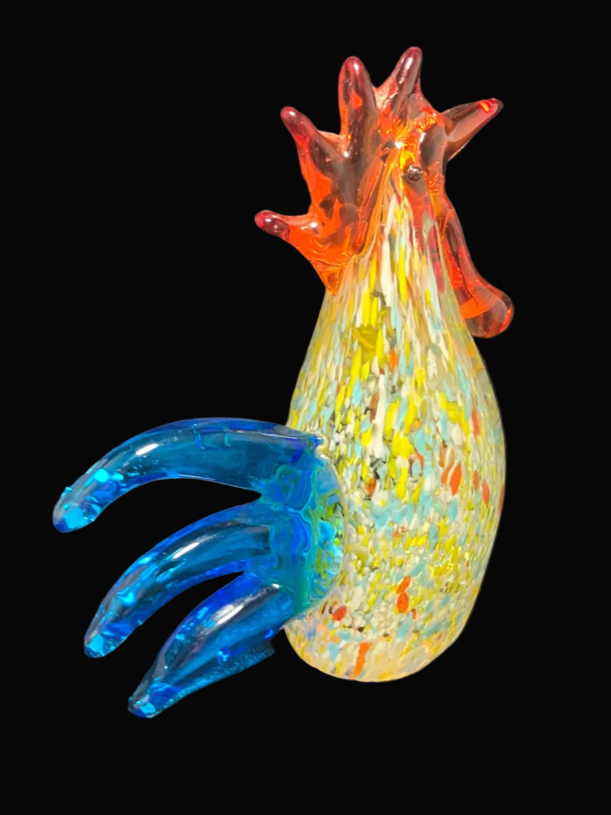 A colorful hand-blown glass rooster figurine with a yellow speckled body, blue claws, and an orange-red spiky crest.