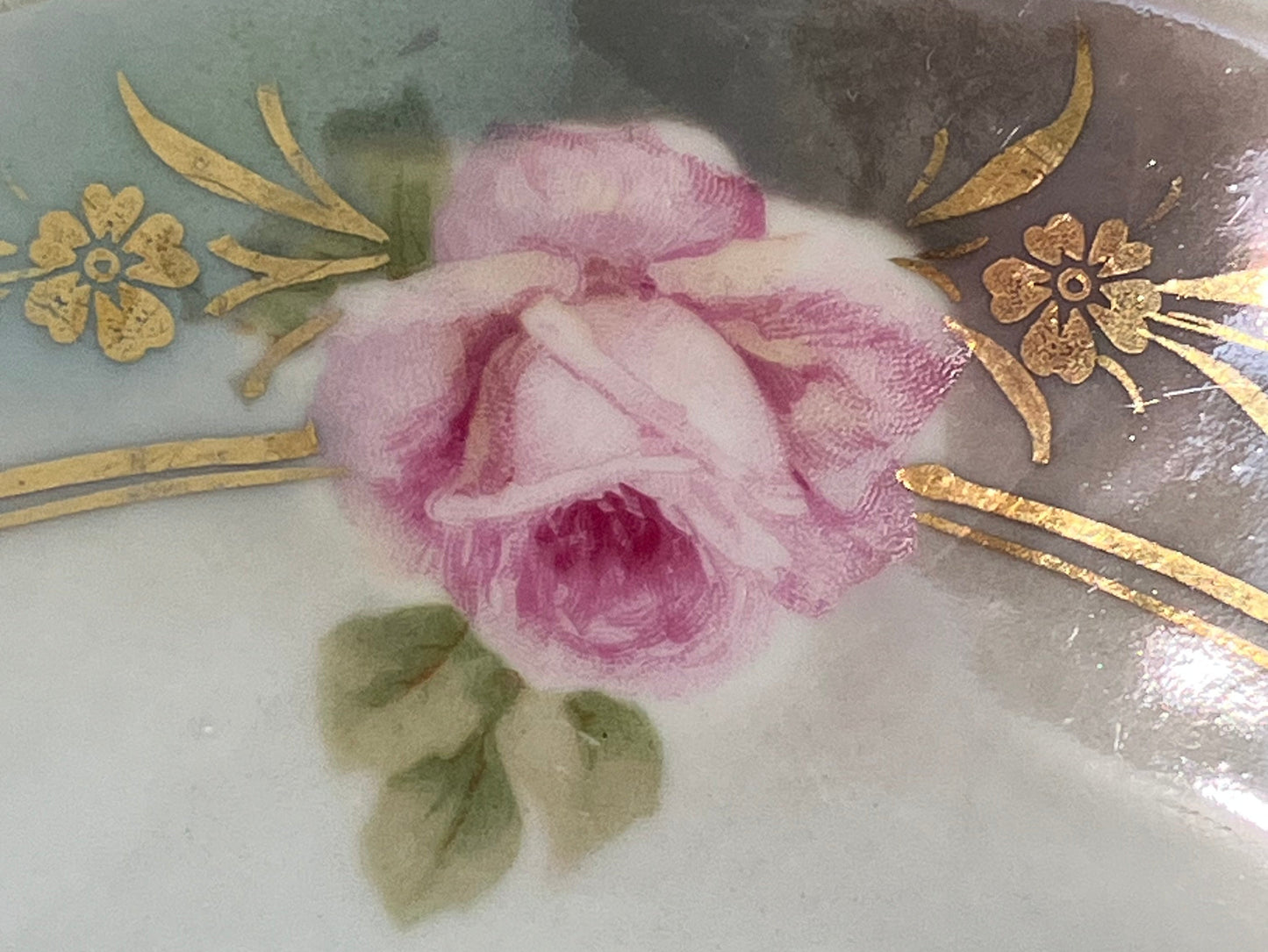 Decorative item with a pink rose and gold floral patterns on a white background