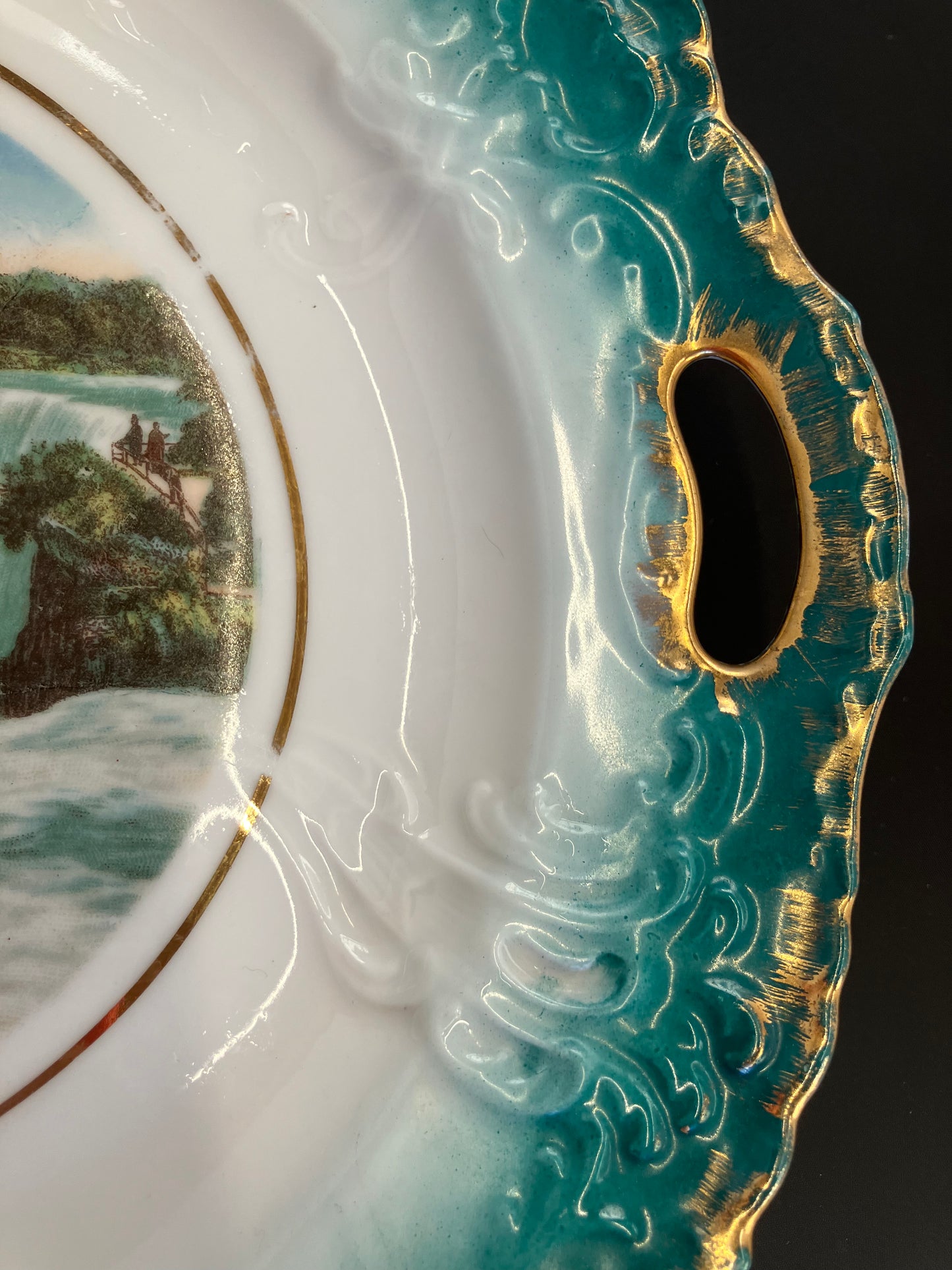 Decorative ceramic item with intricate designs and a scenic view on a dark background