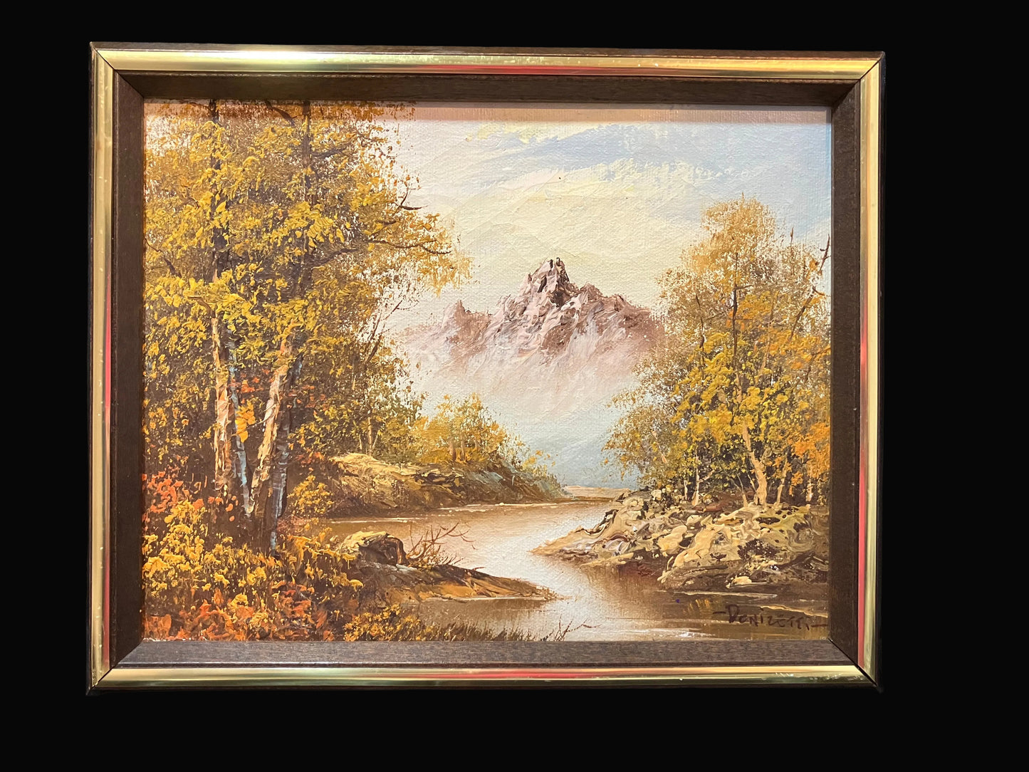 Framed painting of a landscape with trees, a river, and a mountain.