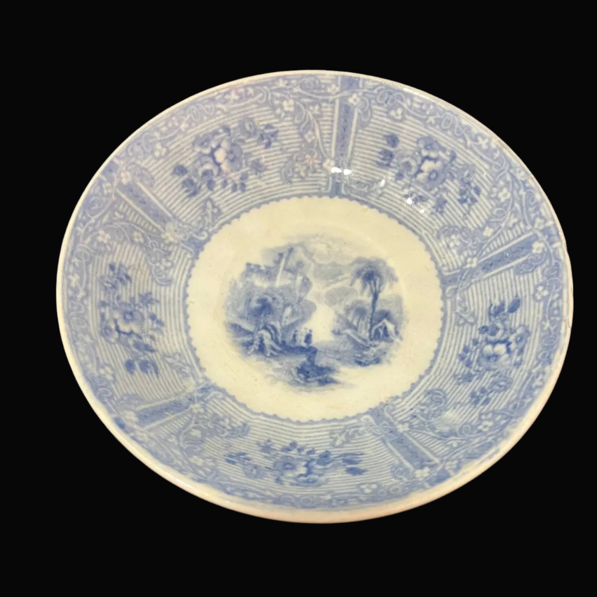A vintage blue and white porcelain tea saucer with intricate floral and landscape designs.