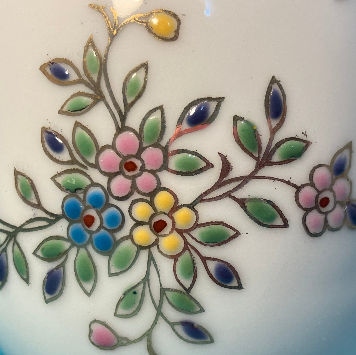 Close-up of floral design on a ceramic item with colorful flowers and leaves.