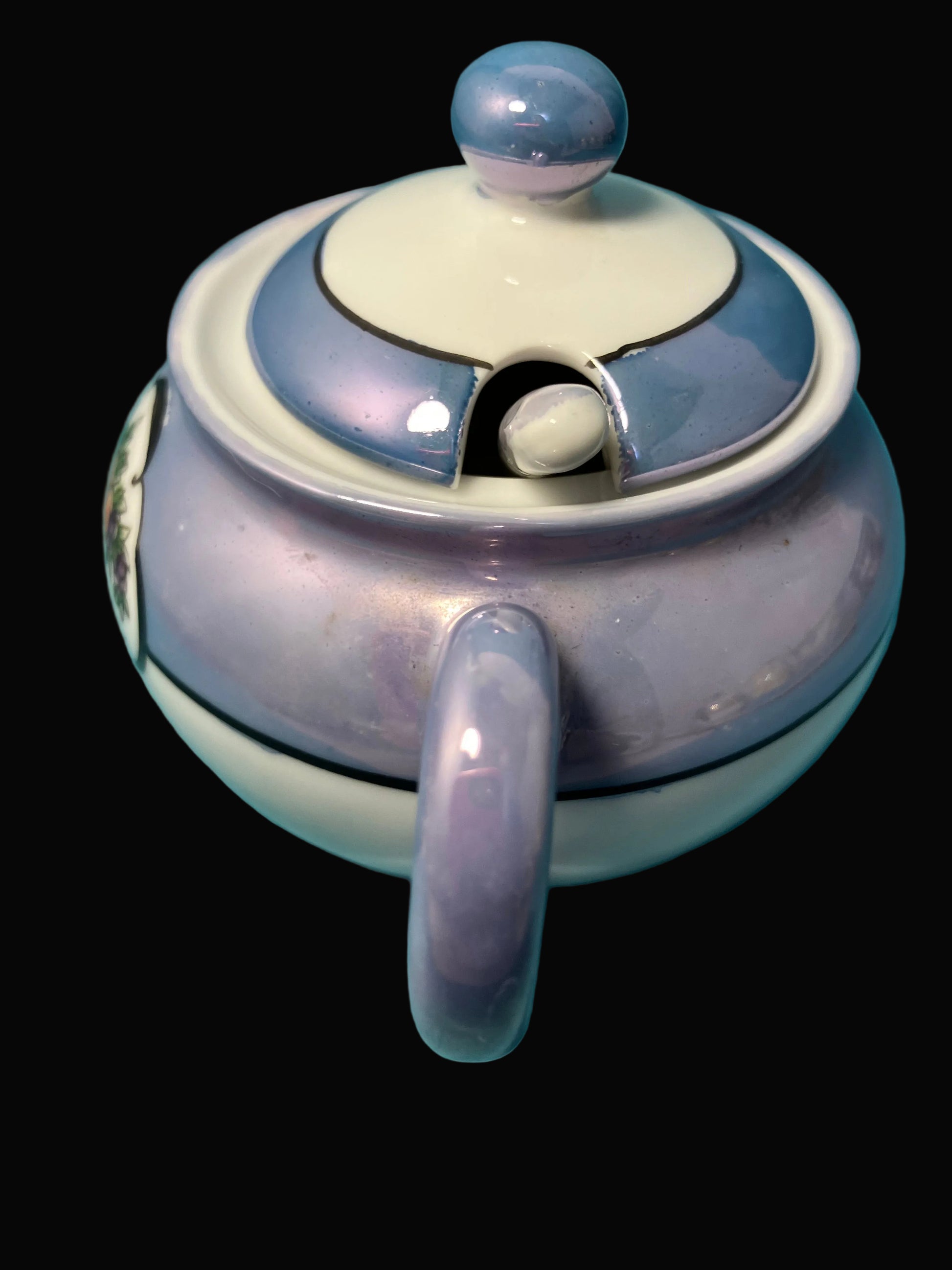 Ceramic mustard pot with a handle and lid on a black background