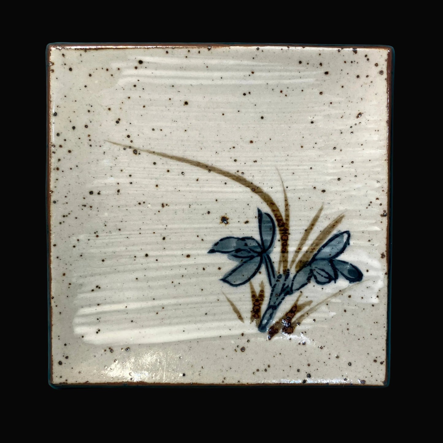 Ceramic sushi plate with a floral design on a speckled beige background