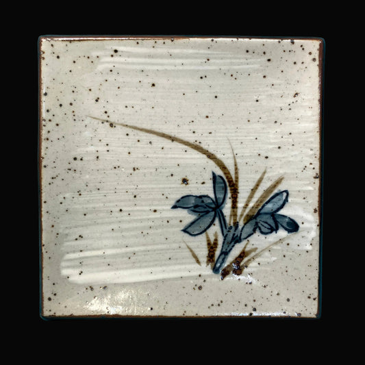 Ceramic sushi plate with a floral design on a speckled beige background