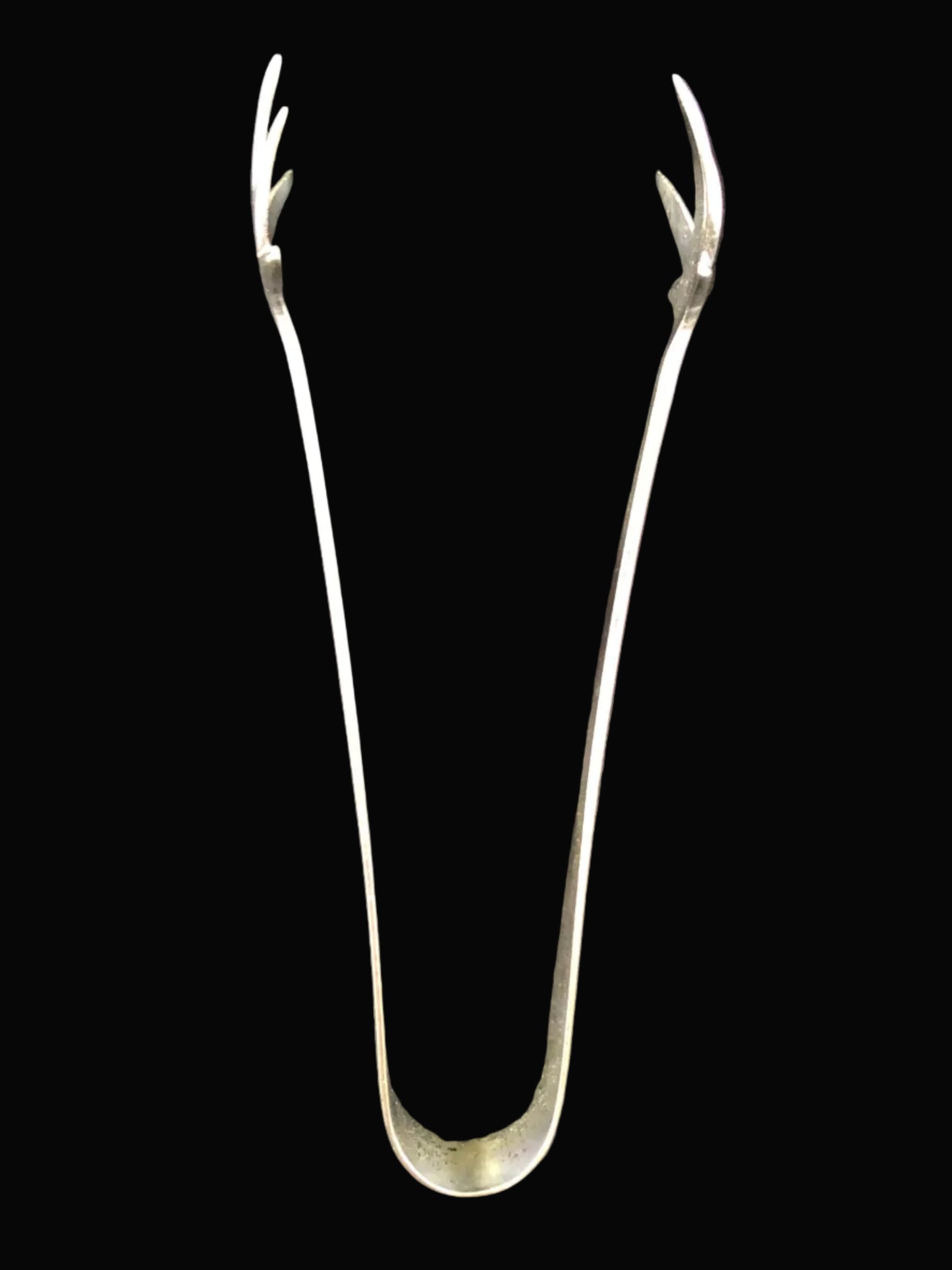 A pair of long metal tongs with forked tips, shown standing upright on a dark  background.
