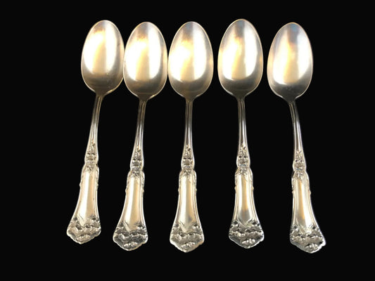Set of five silverplate spoons with decorative handles on a black background
