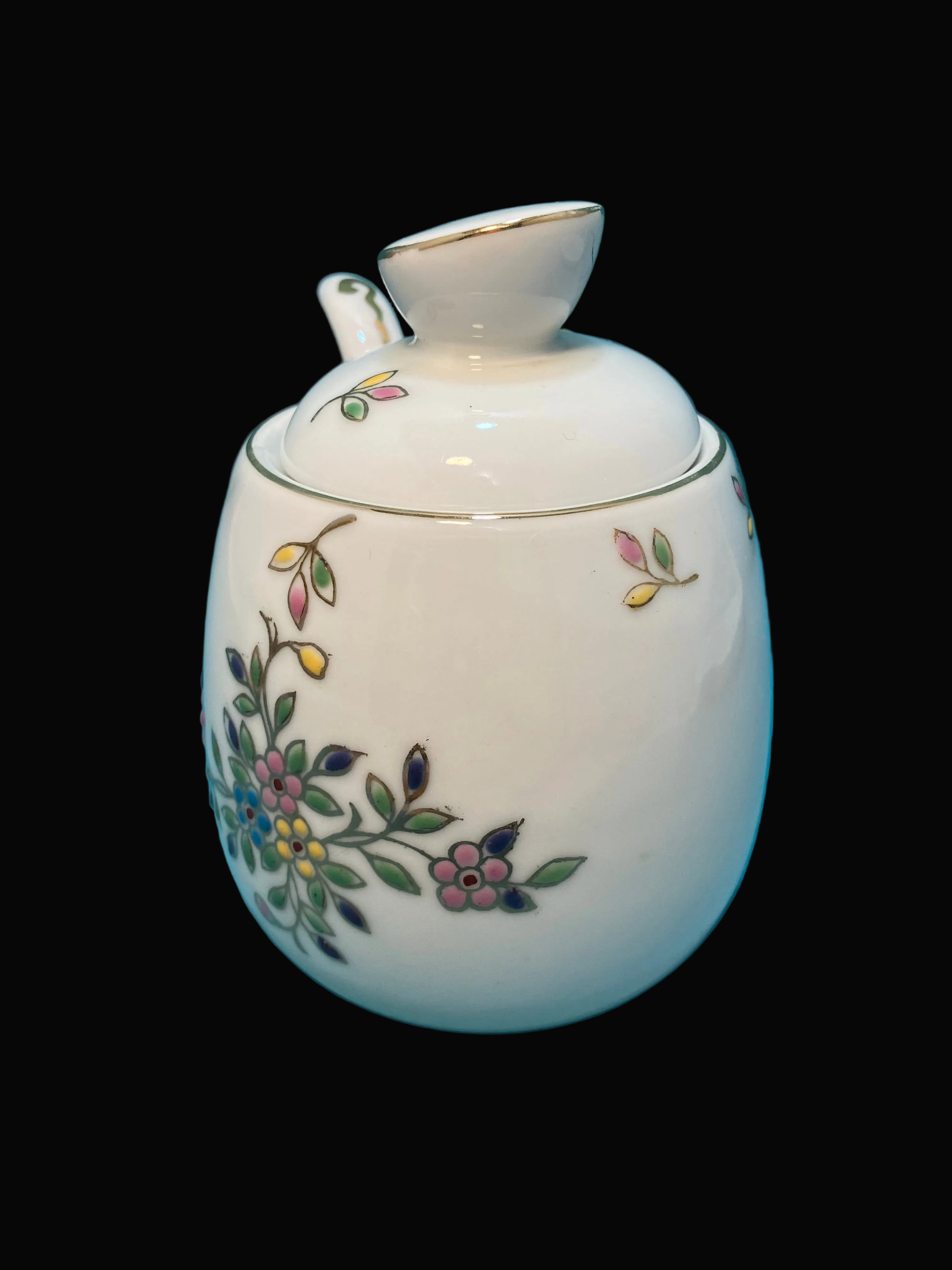 White ceramic jar with floral designs on a black background