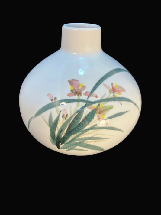 White ceramic vase with floral design on a dark fabric background