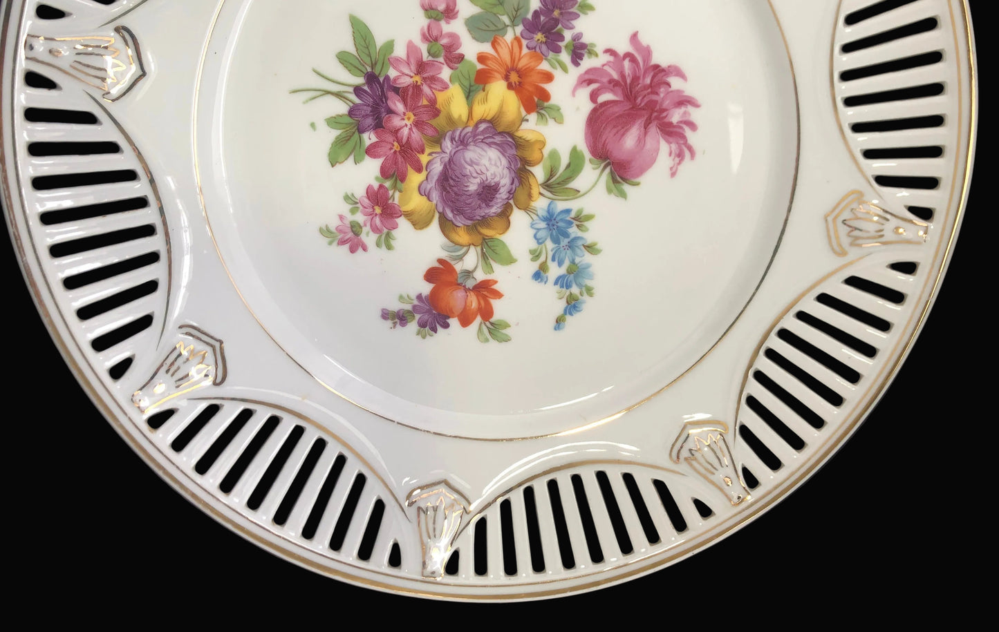 Decorative plate with floral design and striped rim on a dark background