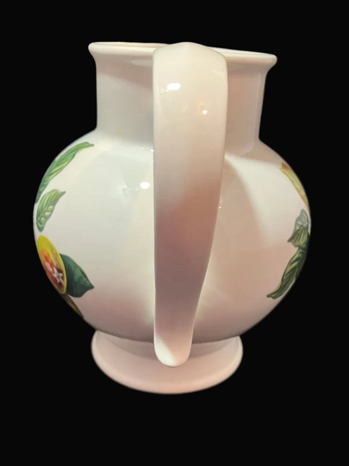 A white ceramic pitcher with a floral and fruit pattern.
