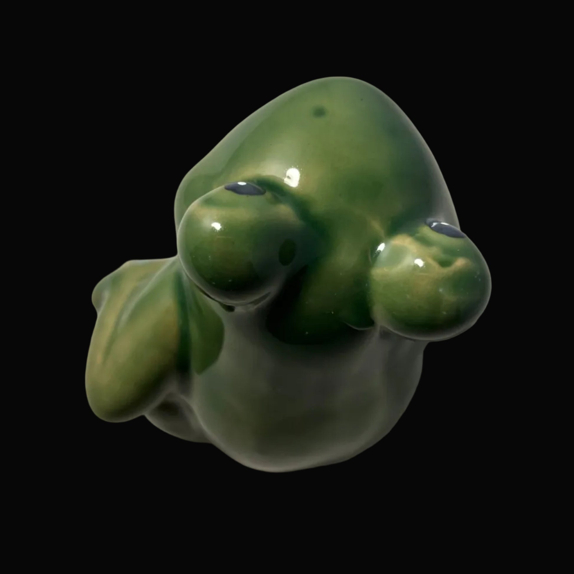 Green ceramic frog on a black background