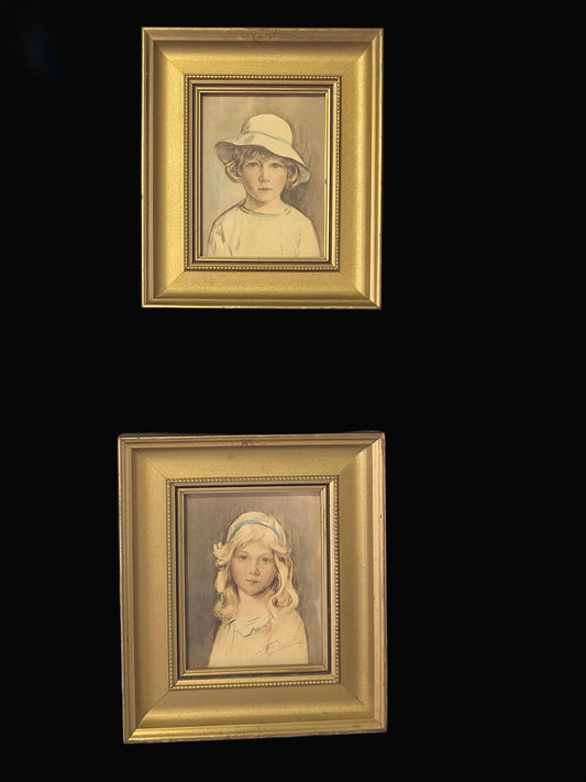 Two framed portraits of children by Arthur Garratt on a black background