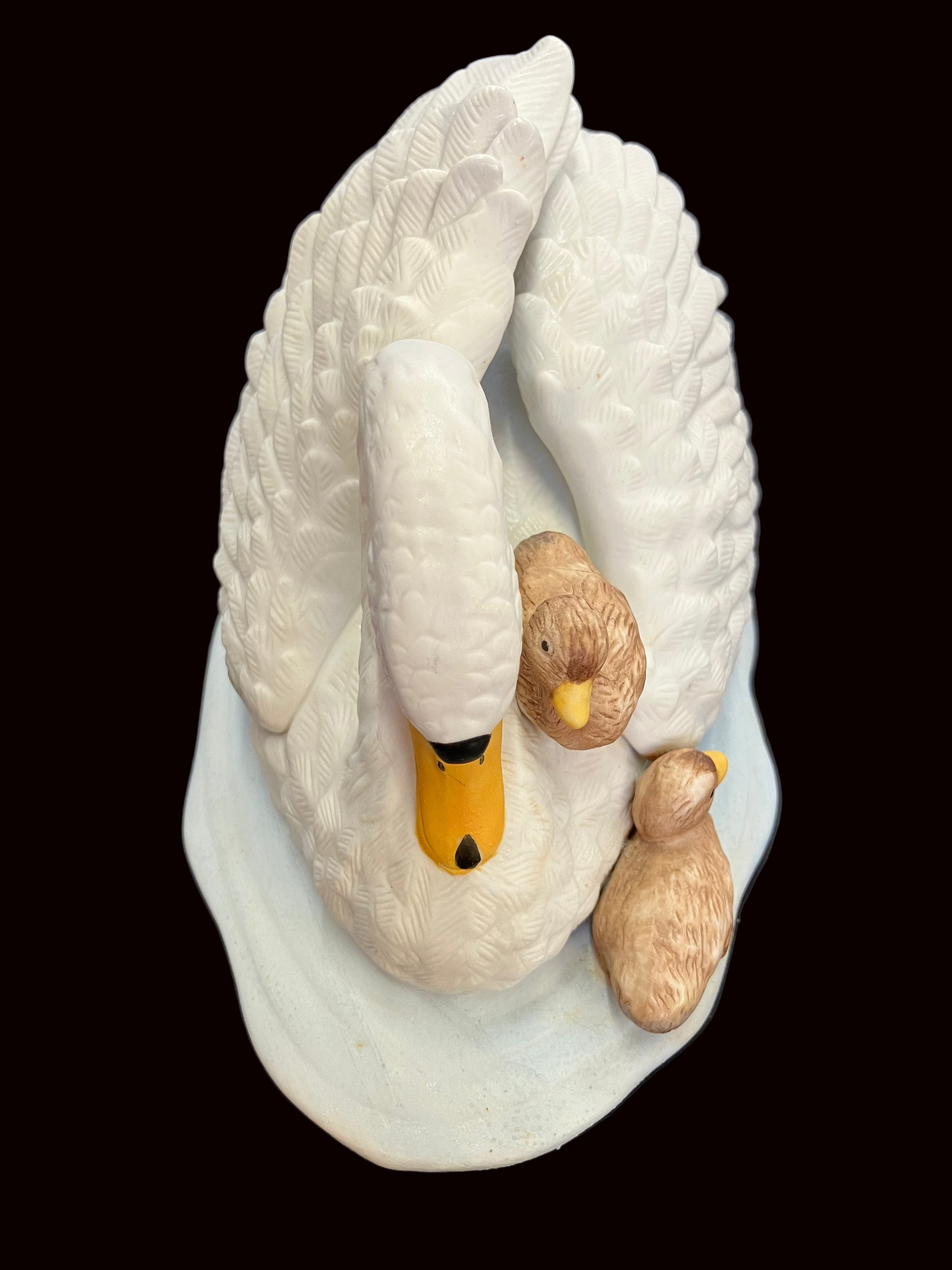 Decorative sculpture of a swan with two cygnets on a dark background