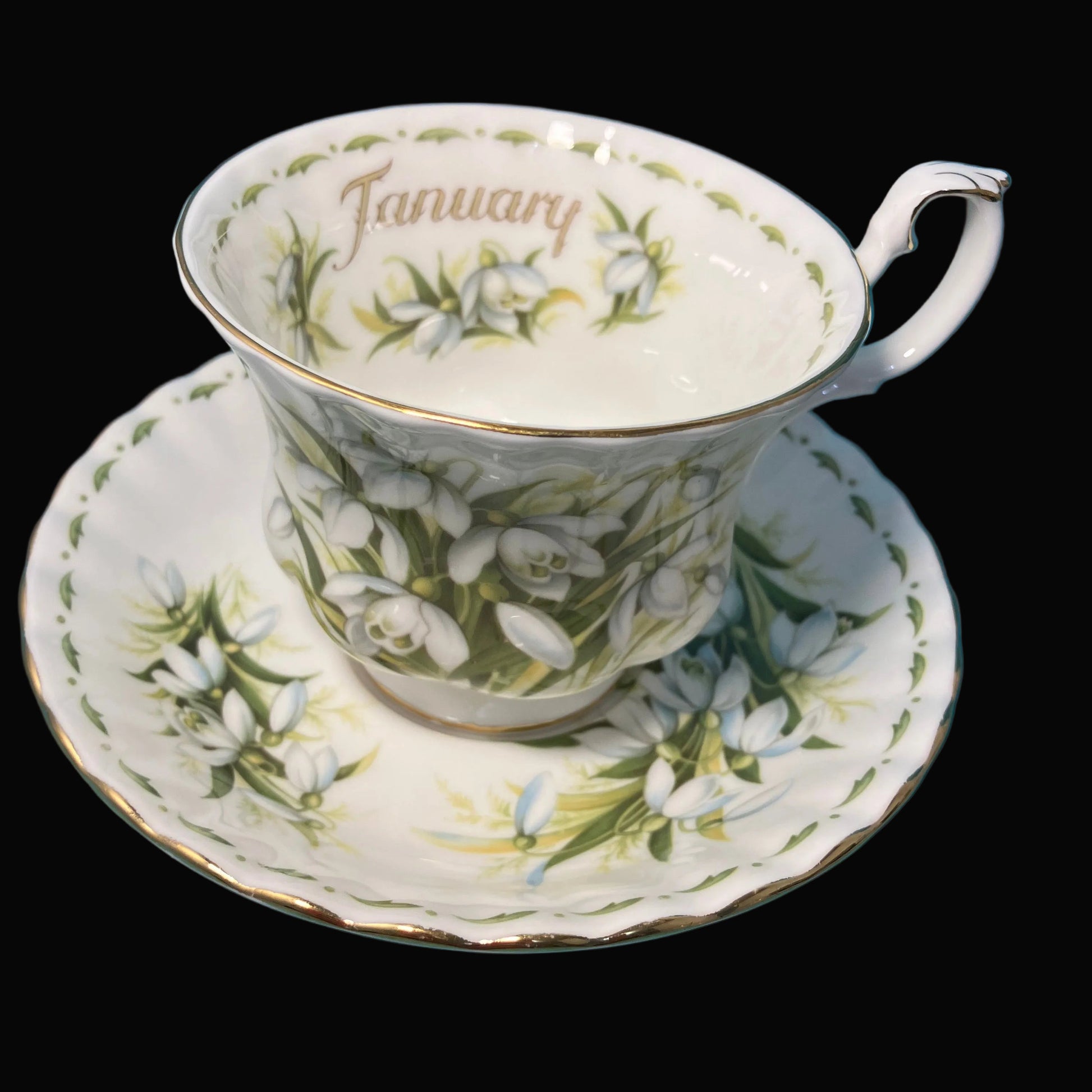 Teacup and saucer with floral design and 'January' text on a black background
