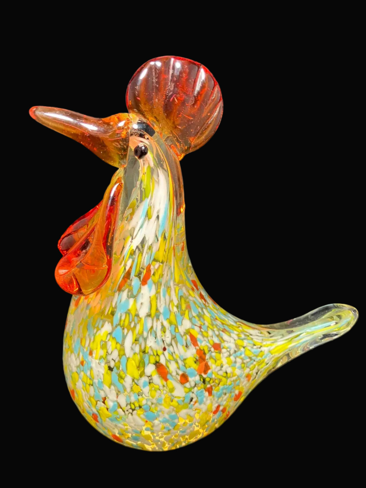 A hand-blown glass rooster figurine with a vibrant yellow, green, and blue speckled body and reddish-orange comb and wattle.