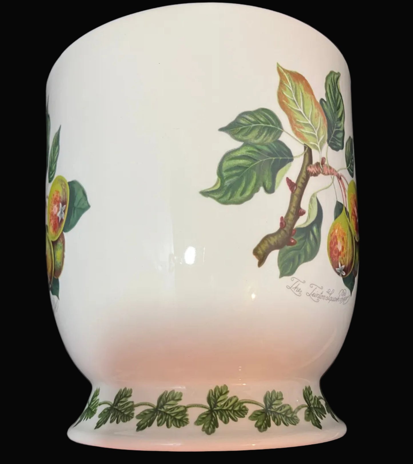 A white ceramic planter decorated with green leaves and orange-yellow fruit illustrations.