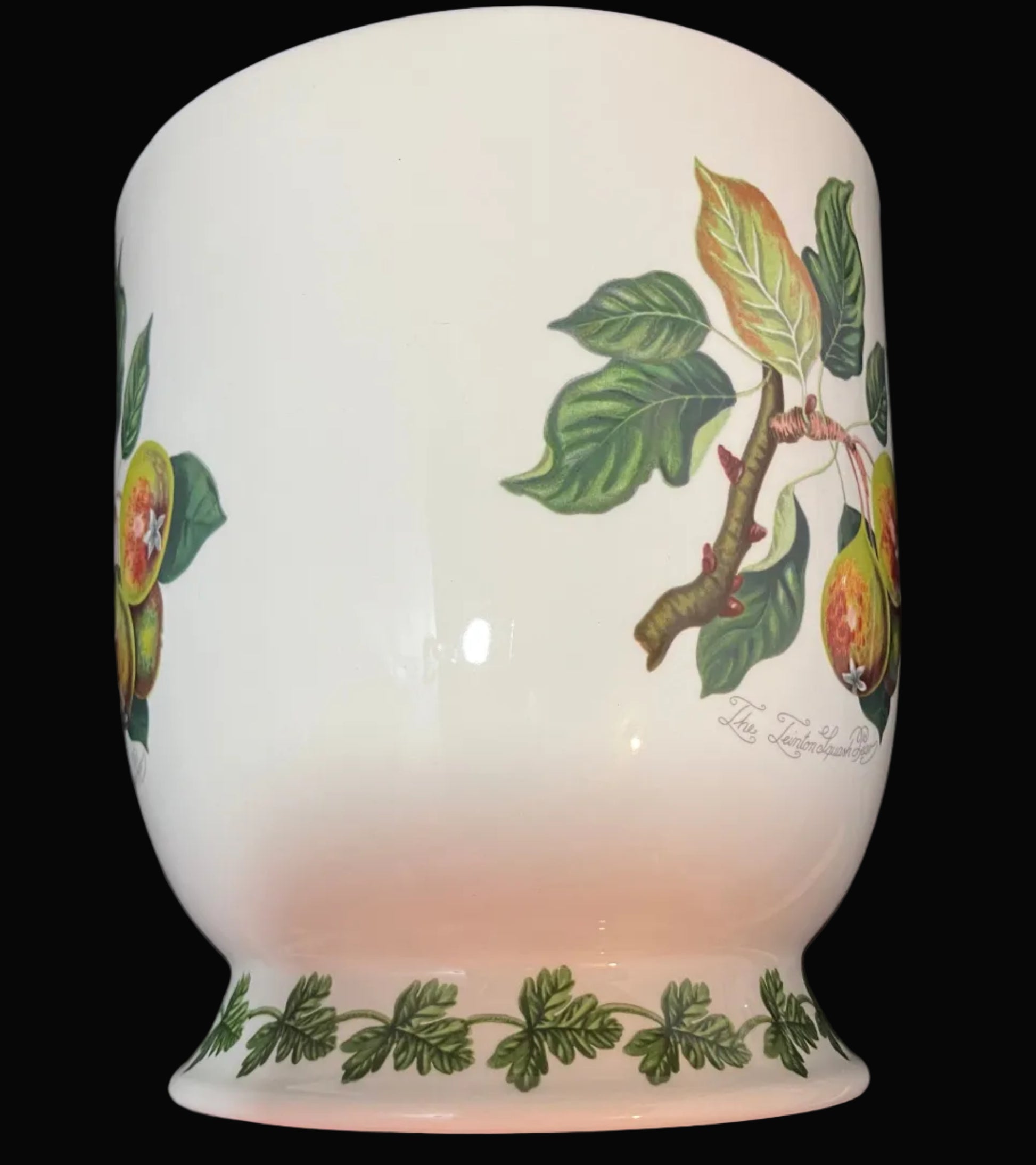 A white ceramic planter decorated with green leaves and orange-yellow fruit illustrations.