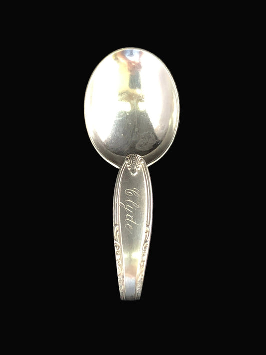 A vintage sterling silver spoon with decorative engraving on the handle.