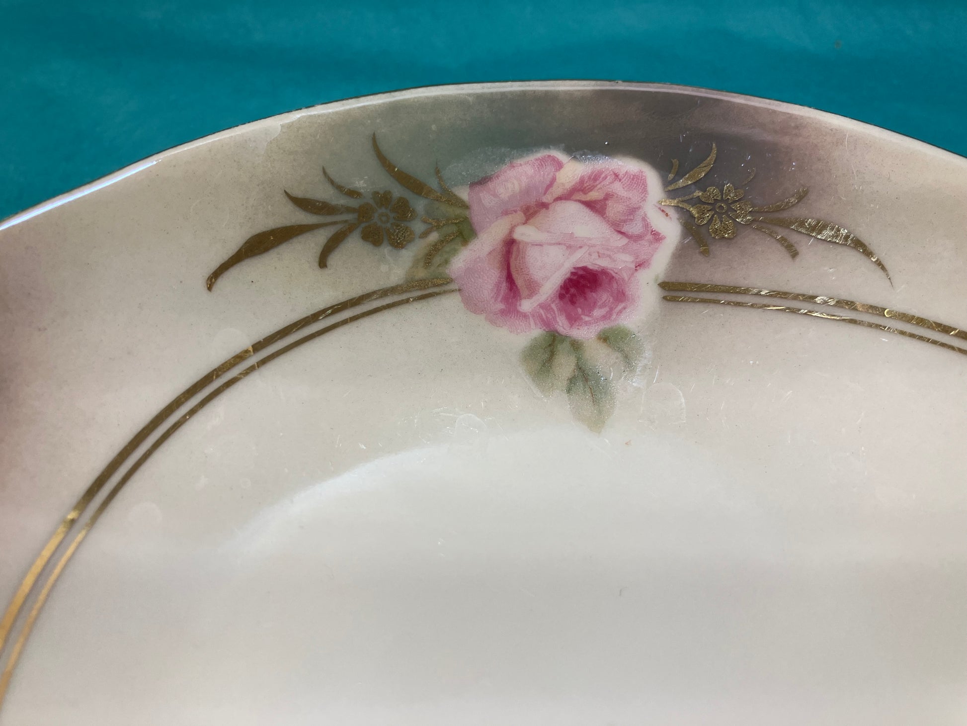 Decorative plate with a pink rose and gold floral patterns on a blue background
