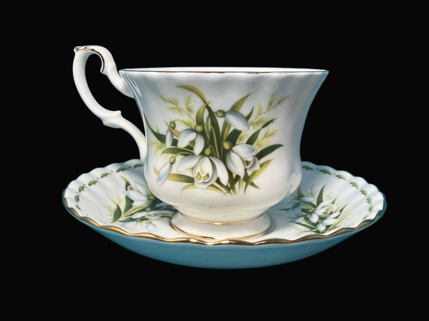 Teacup and saucer with floral design on a black background