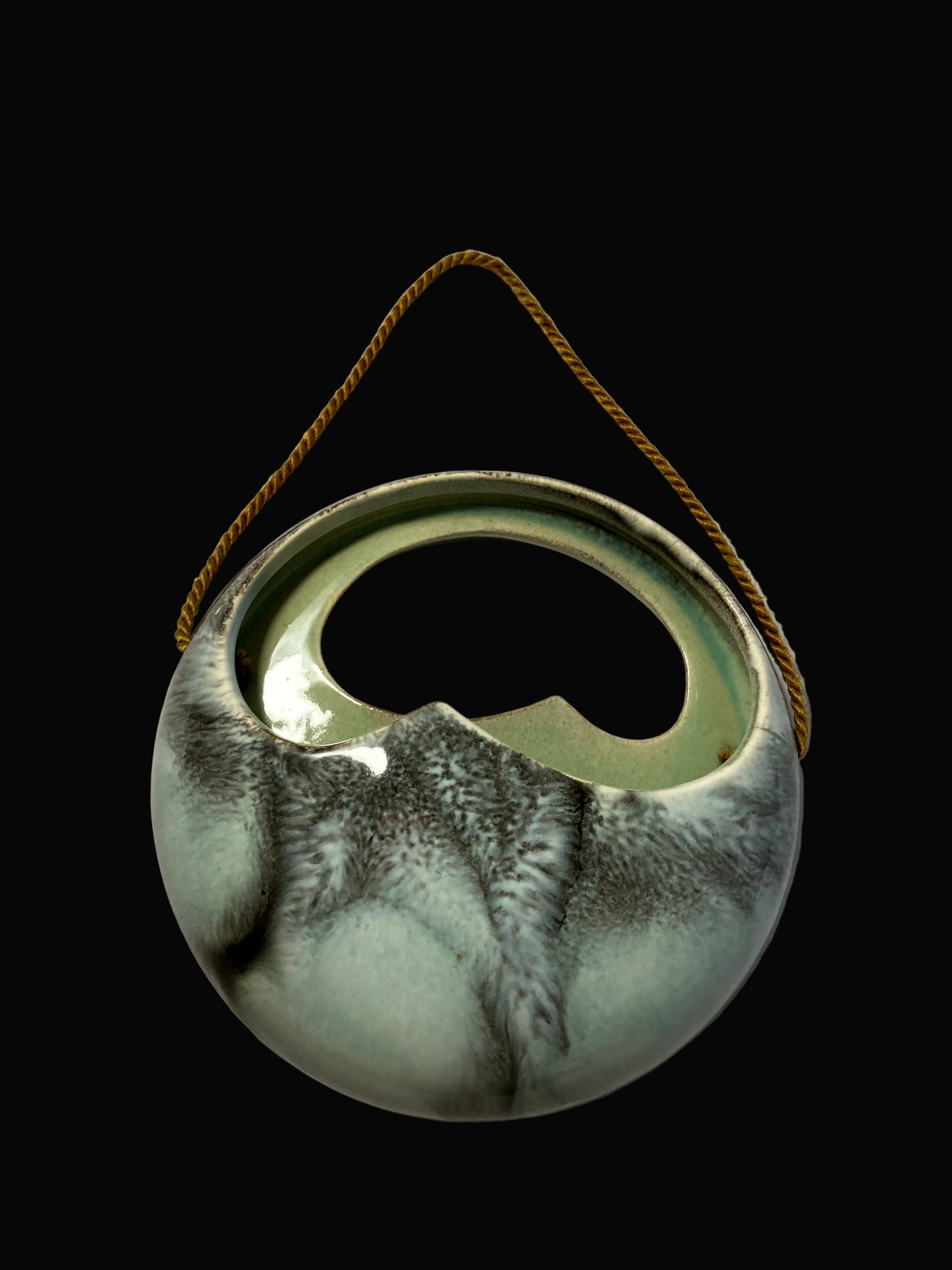 Ceramic hanging planter with a rope handle on a black background