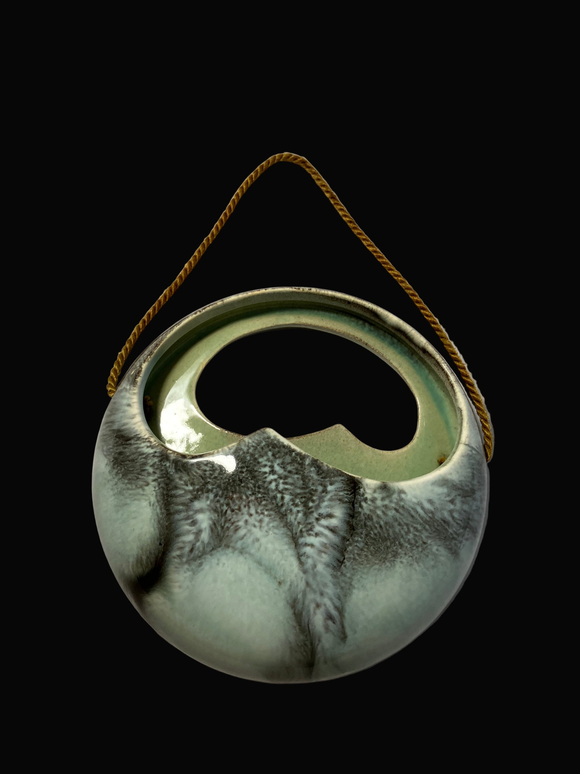 Ceramic hanging planter with a rope handle on a black background