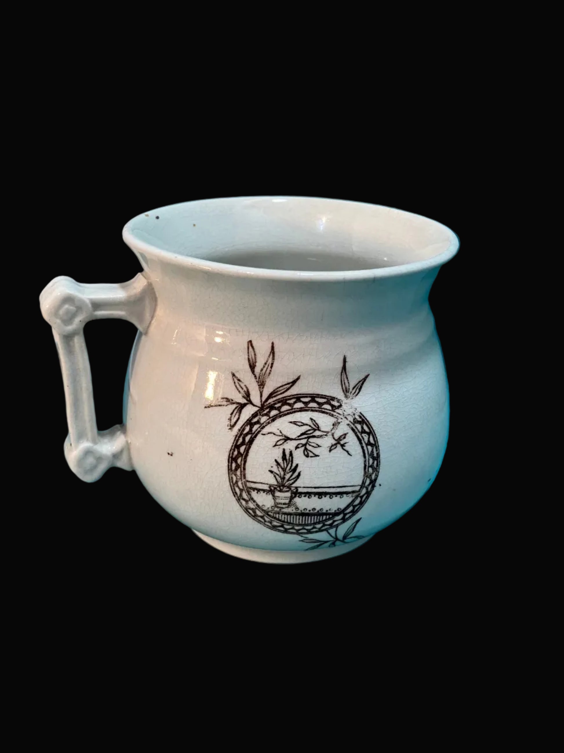 White ceramic mug with decorative handle and brown design on a white background