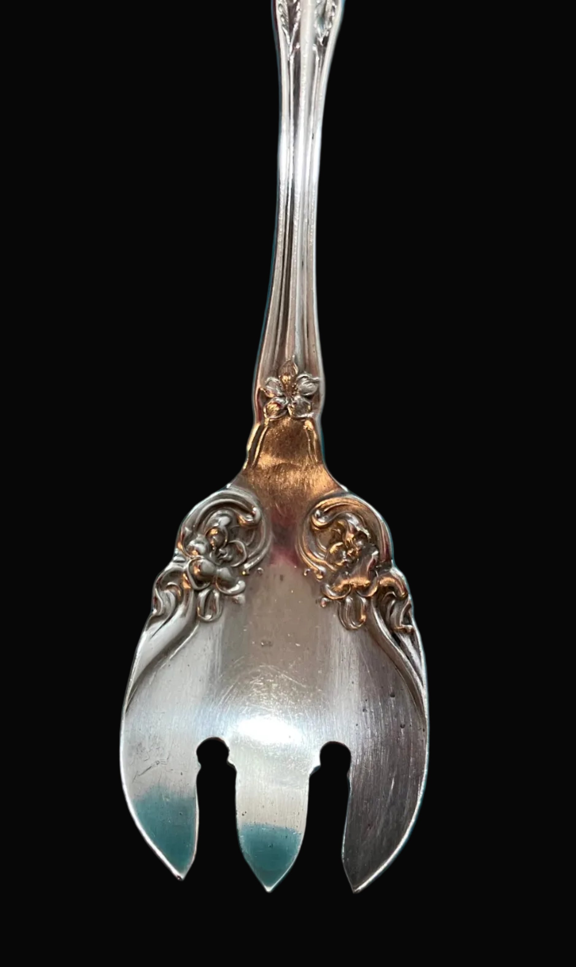 Decorative silver spoon with intricate designs on a black background
