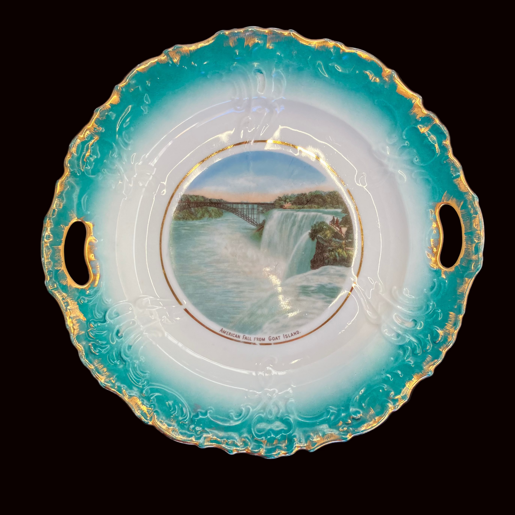 Decorative plate with a scenic design of a waterfall and gold rim on a black background