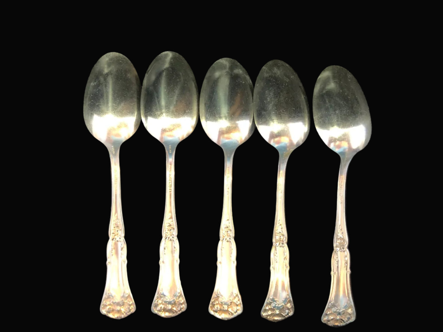 Set of five silverplate spoons on a dark background
