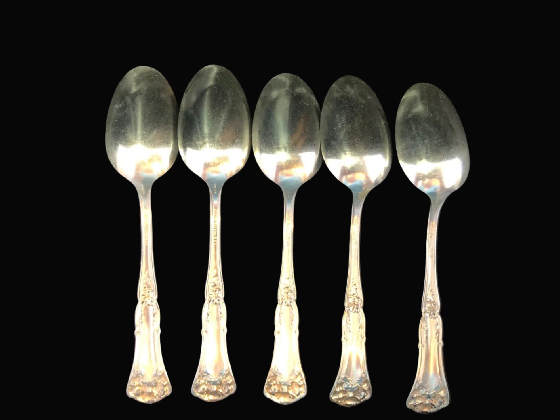 Set of five silverplate spoons on a dark background