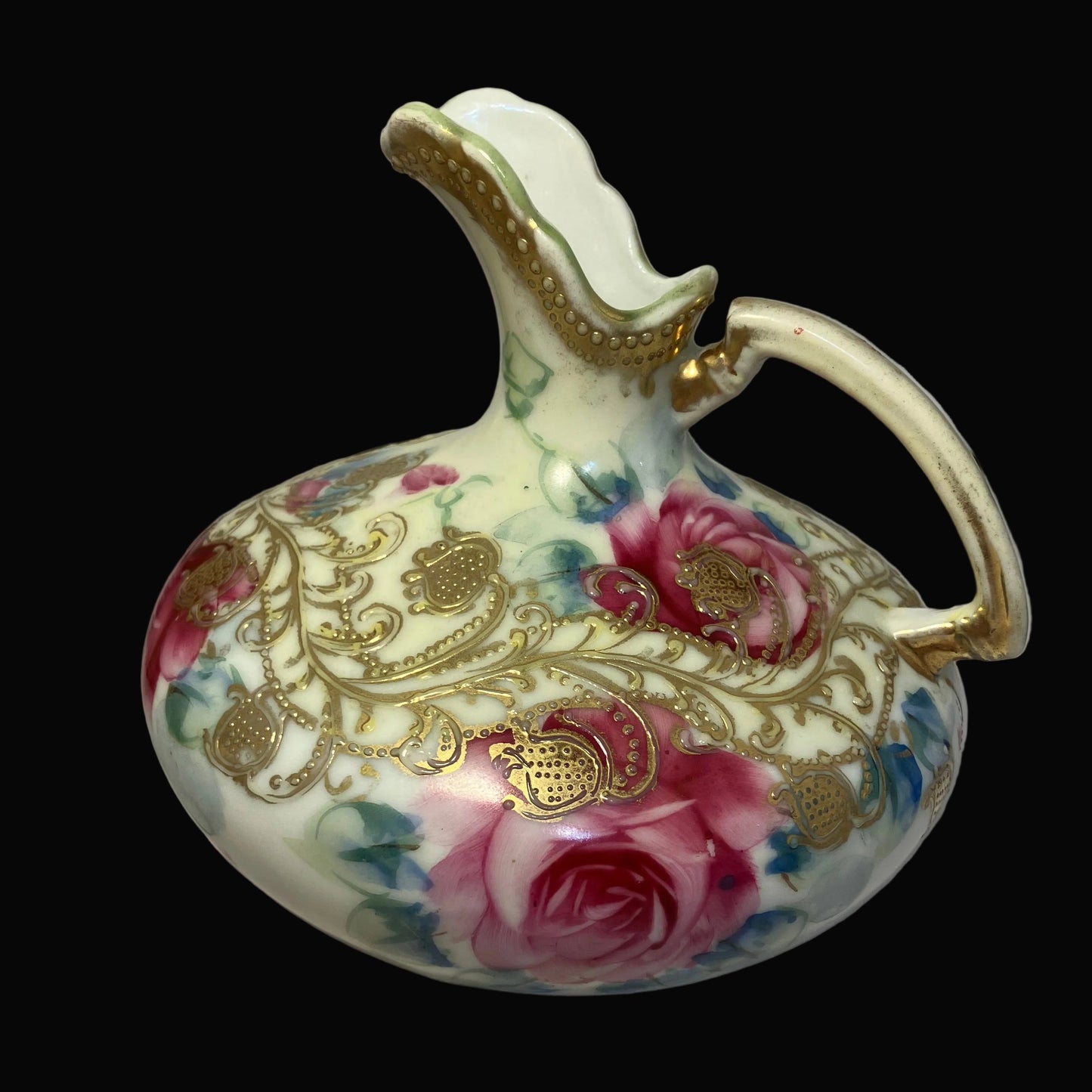 Decorative ceramic pitcher with floral patterns and gold accents on a black background