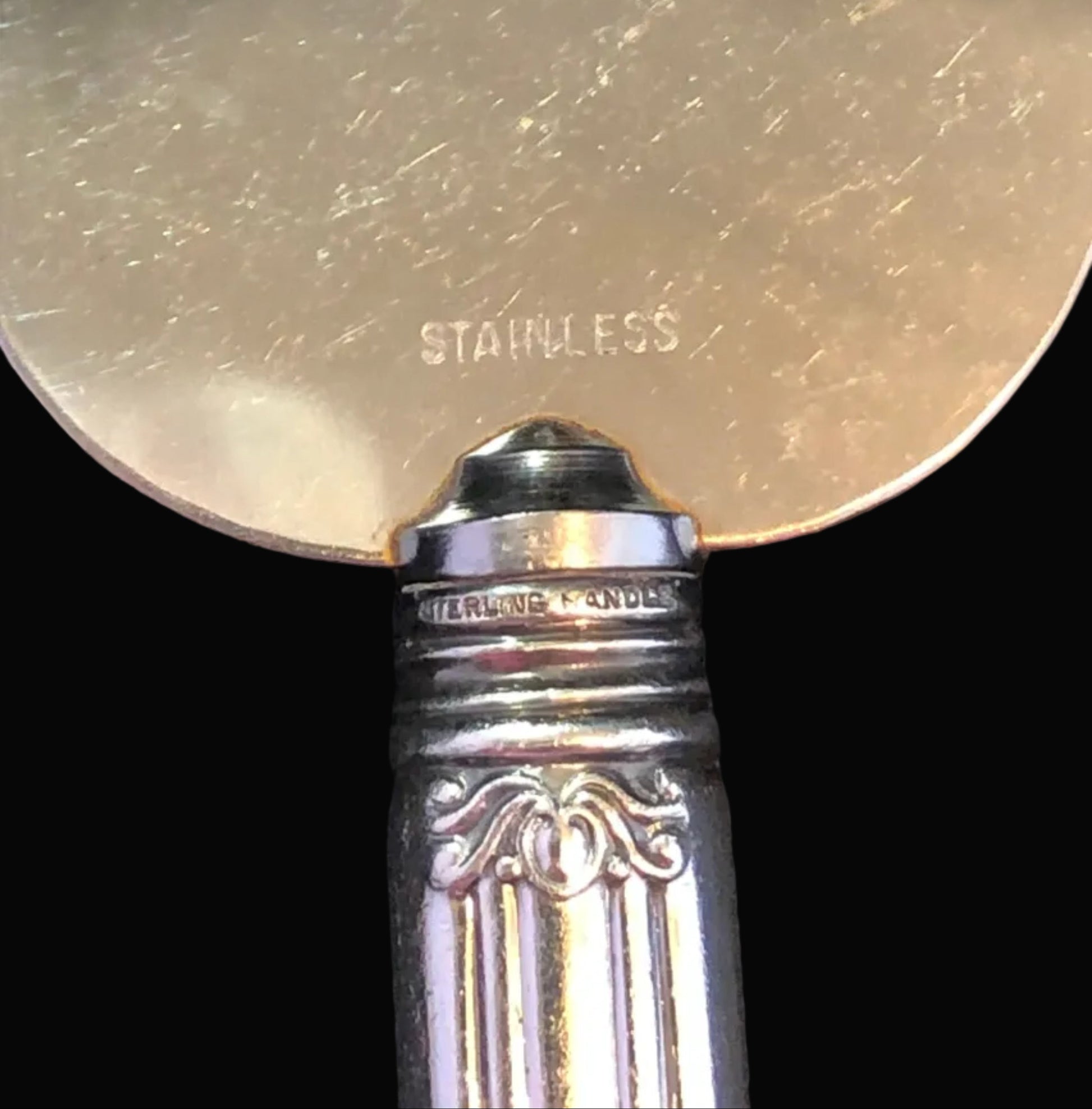 Close-up of a silver object with 'Stainless' engraving under a magnifying glass.
