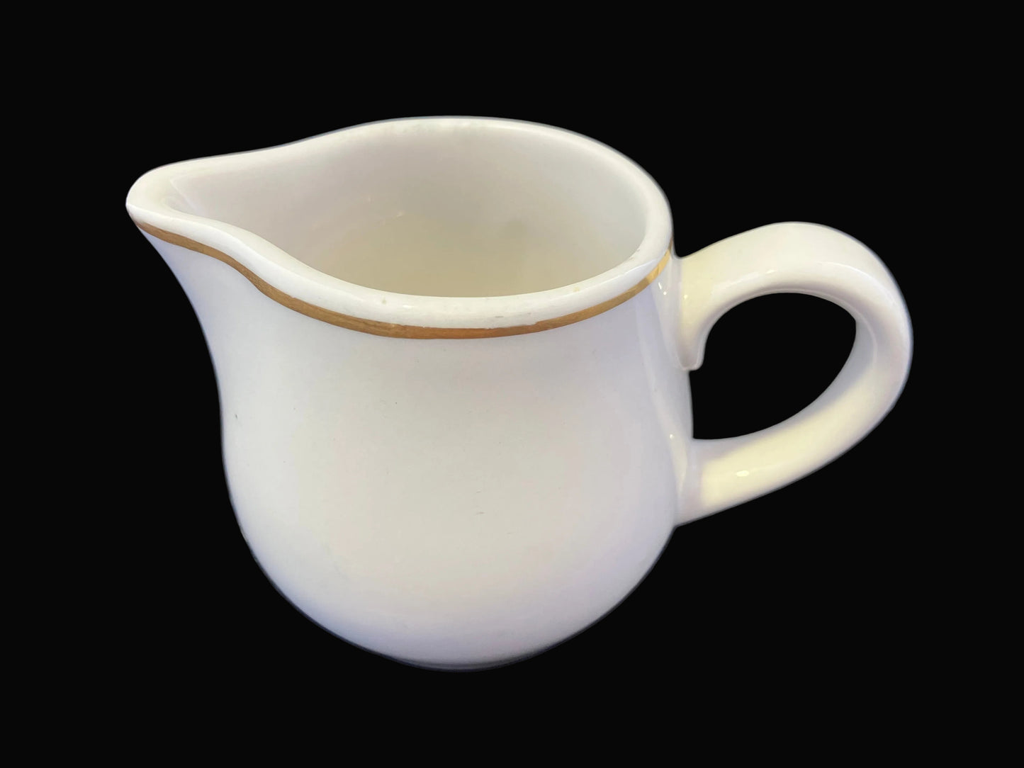 White ceramic pitcher with a handle on a dark fabric background