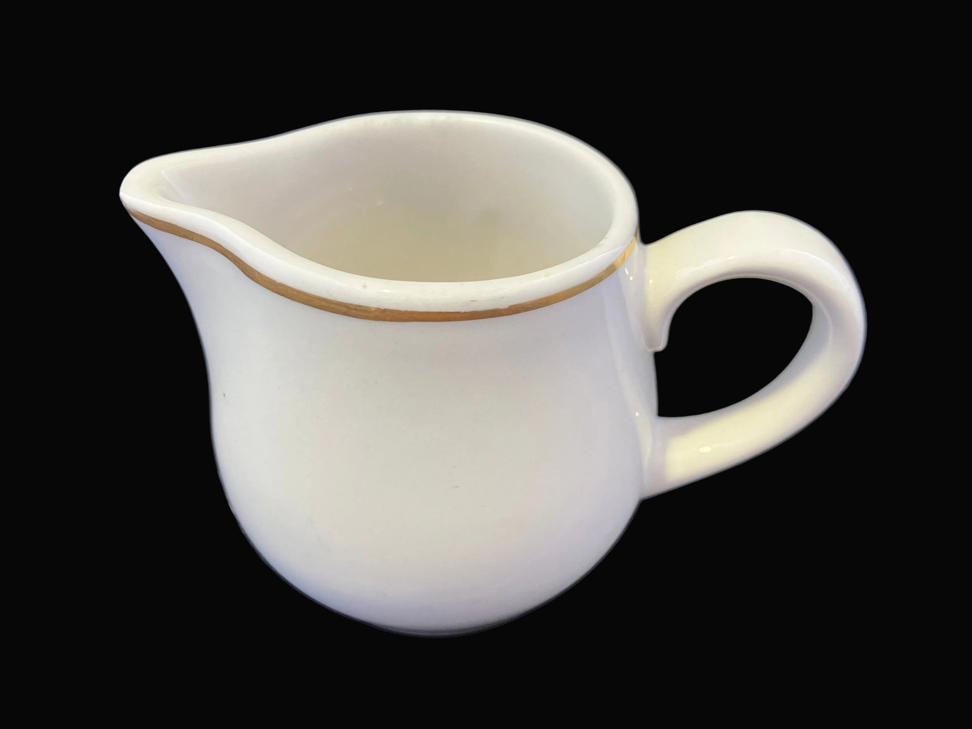 White ceramic pitcher with a handle on a dark fabric background
