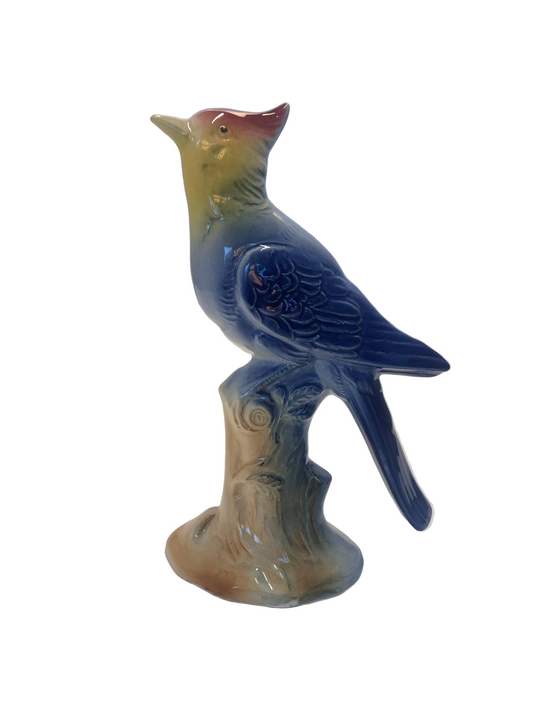 Ceramic bird figurine possibly Royal Copley on a branch with a plain background