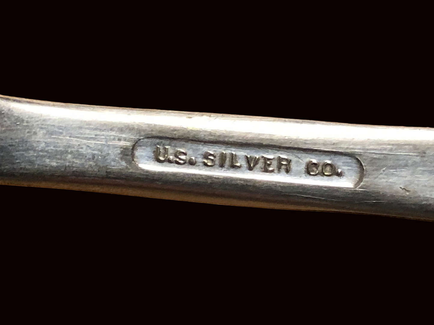Close-up of a silverplate spoon with 'U.S. Silver Co.' engraving on it
