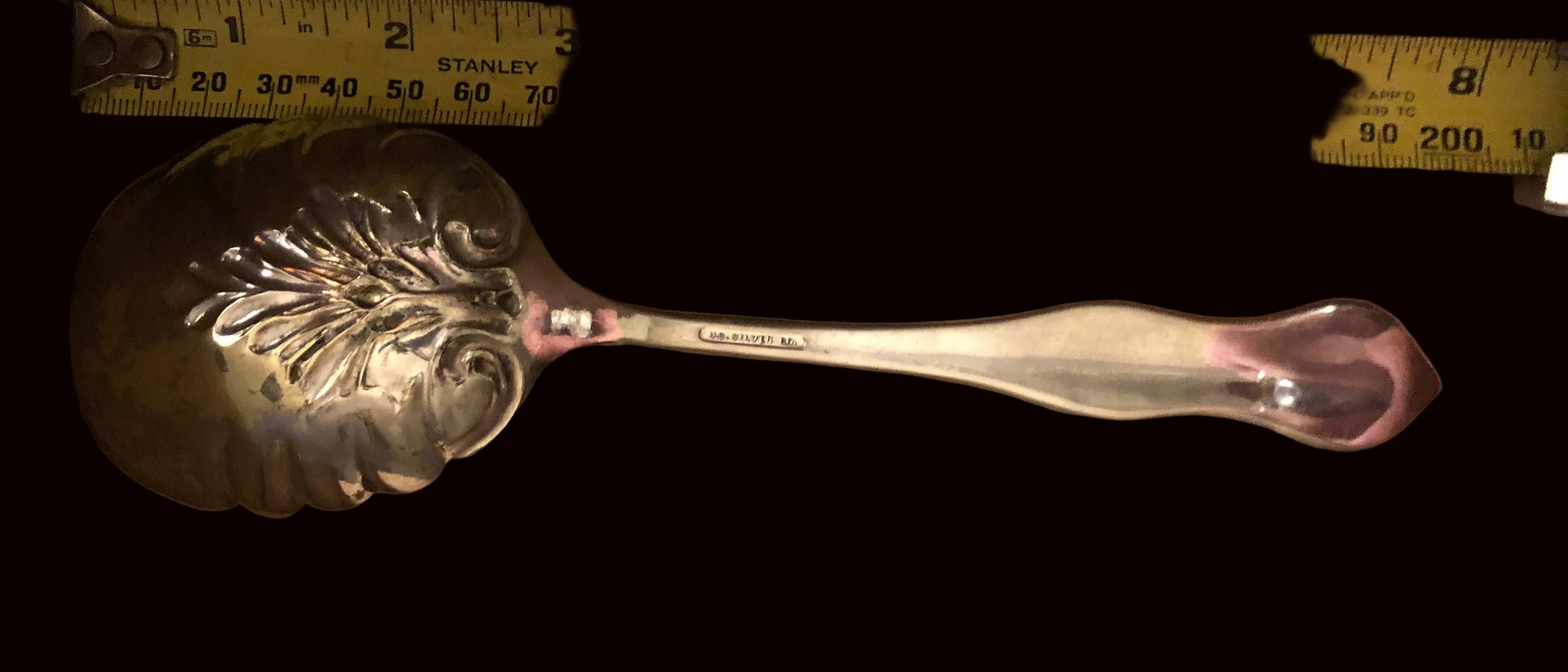 Silver decorative spoon next to a ruler