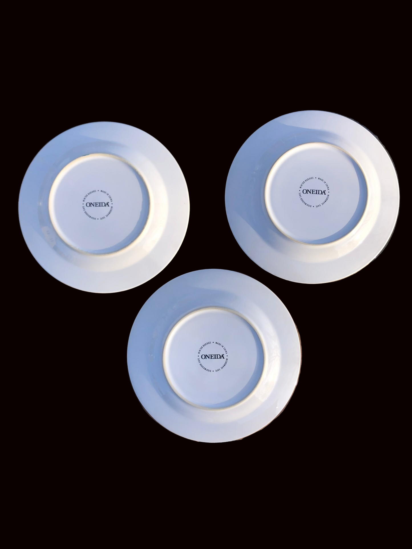 Three white plates with blue rims on a black background