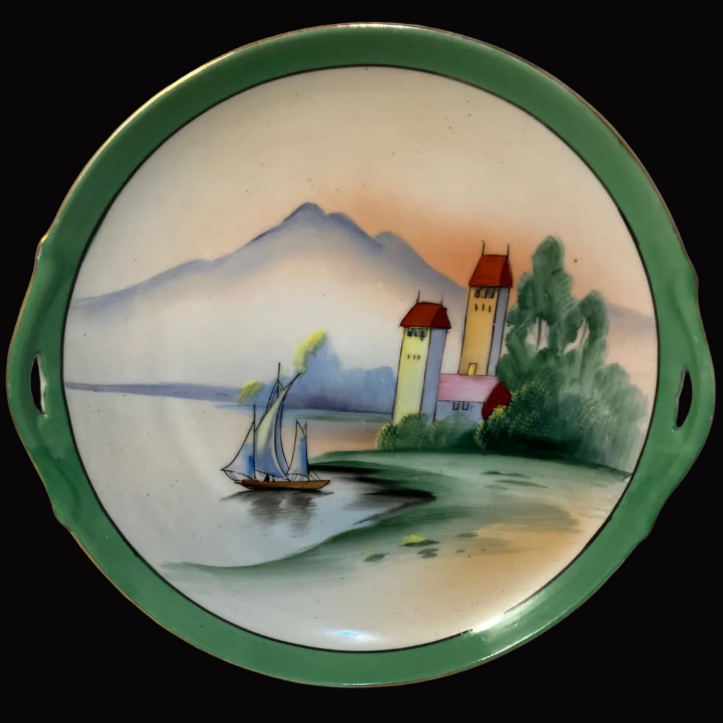 Decorative plate with a scenic design of a castle, sailboat, and mountains 