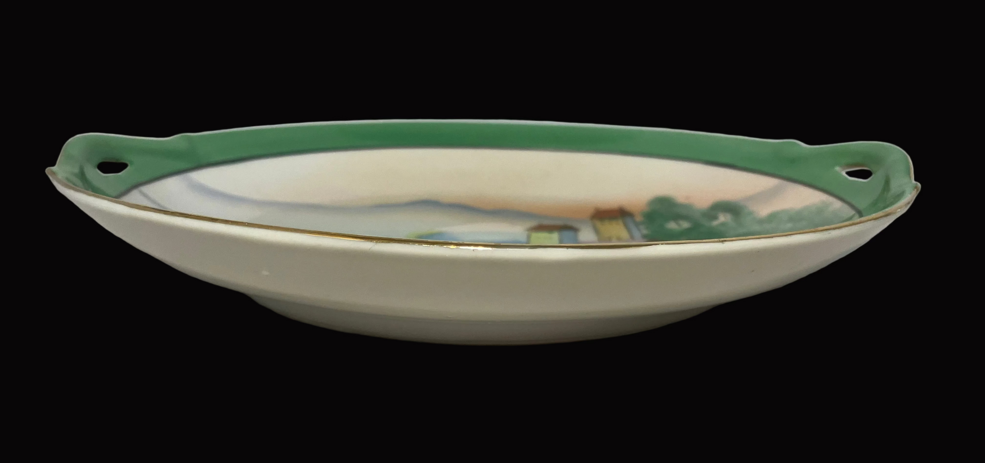 Ceramic dish with green rim and handle on a white surface