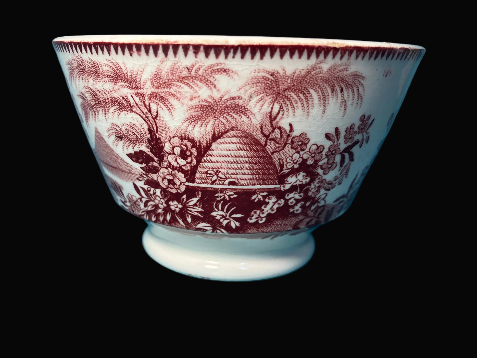 White ceramic bowl with red  transferware floral and beehive design 